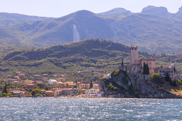 Idyllische Küstenlandschaft in Italien vom Wasser aus eingefangen Blaues Wasser und ein süßes Dorf am Lago di Garda Malcesine