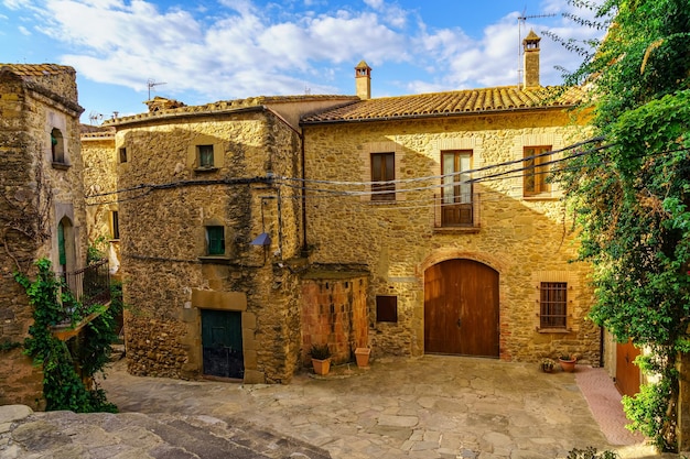 Idyllische Steingebäude mit Kletterpflanzen und Holztüren im mittelalterlichen Dorf Madremanya Girona Katalonien
