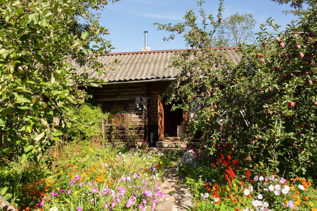 Idyllischer und malerischer Sommergarten mit kleinem Holzhaus mit Pfeife in russischer Landschaft.