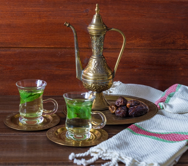 Foto iftar y el concepto de suhoor ramadan, té mentha en tazas de vidrio y dátiles con una tetera antigua