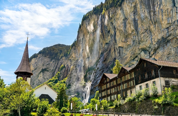 La iglesia de la aldea y las cataratas Staubbach en Lauterbrunnen, el cantón de Berna, Suiza