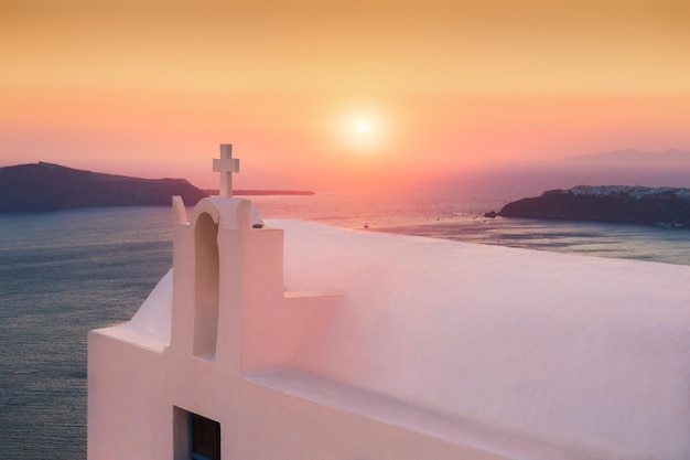 Iglesia blanca al atardecer en la isla de Santorini, Grecia. Paisaje de verano, vista al mar