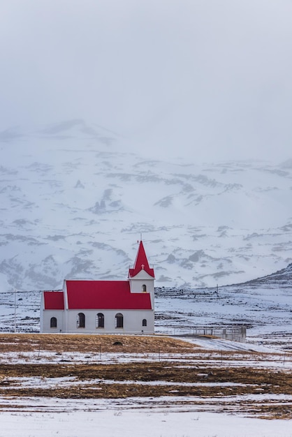 Iglesia blanca con techo rojo en el paisaje nevado de Hellisandur Islandia