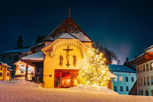 Iglesia católica en Christmas Gruyeres Town Village en Suiza en invierno por la noche