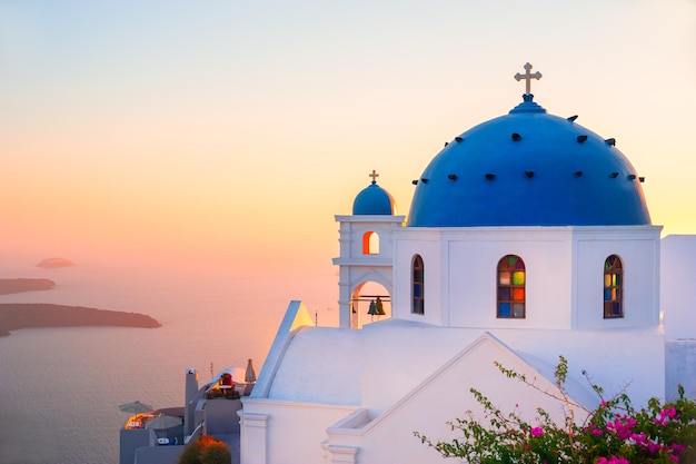 Iglesia con cúpula azul al atardecer en la isla de Santorini, Grecia. Paisaje de verano, vista al mar