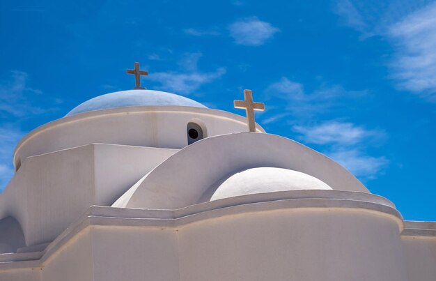 Iglesia grega ortodoxa blanca con cruz en el fondo del cielo azul claro