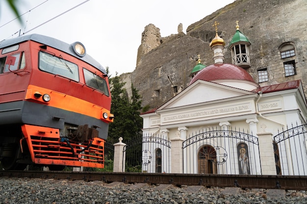 Una iglesia en medio de una montaña de piedra rocosa cerca de un ferrocarril