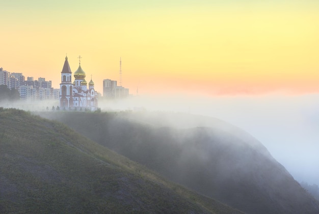 Iglesia Ortodoxa en la niebla de la mañana sobre un escarpado acantilado costero Krasnoyarsk Siberia Rusia