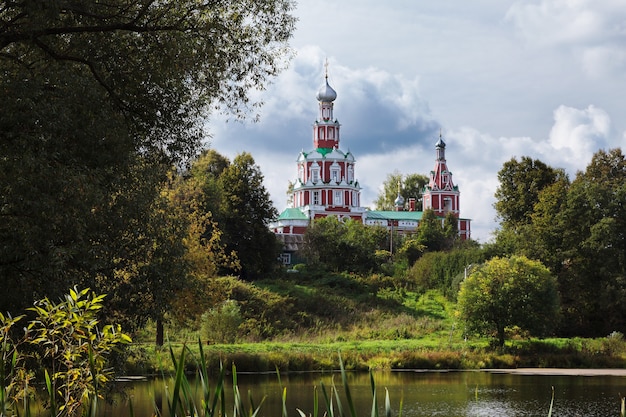 Iglesia ortodoxa roja cerca del lago en la aldea de Sofrino, Rusia