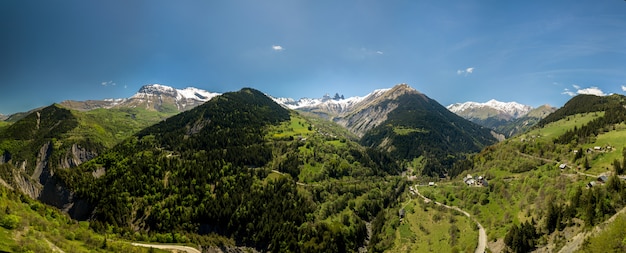 Iglesia en un pueblo de los Alpes franceses con montañas de 3000 metros de altura. Prados verdes en primavera. panorámica de drones