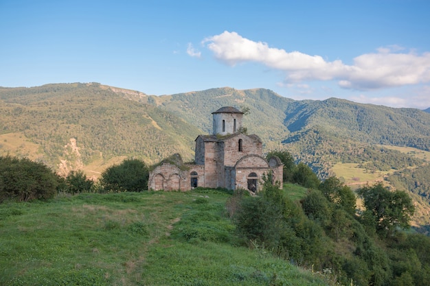 Iglesia vieja en las montañas, en el parque nacional Dombai, Cáucaso, Rusia. Paisaje de verano, clima soleado, espectacular cielo azul y día soleado