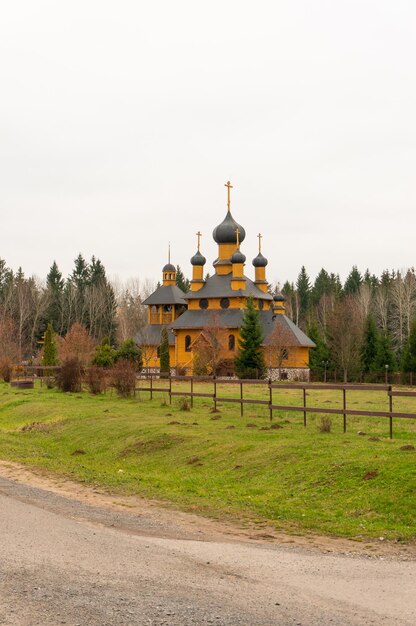 Foto igreja amarela de madeira com floresta e campo na zona rural