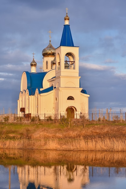 Igreja branca com telhado azul na margem do lago, a igreja ao pôr do sol