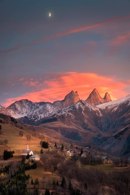 Igreja e lua mostradas nas montanhas dos alpes franceses.