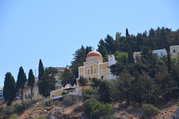 Igreja grega no topo da montanha rodeada de árvores verdes, ilha de symi