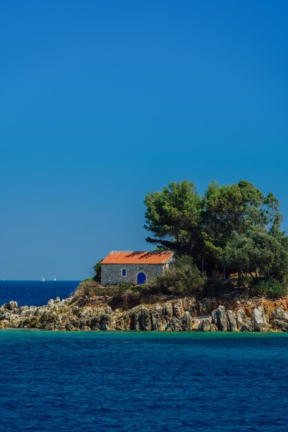 Igreja ortodoxa grega construída em pedra com telhado de telhas vermelhas construída em uma ilha rochosa