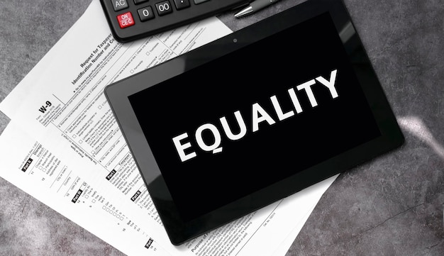 Igualdade em um tablet preto e com formulários fiscais e calculadora