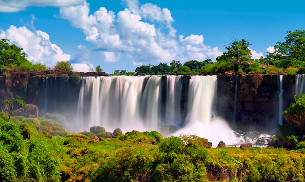 Iguazu wasserfälle in argentinien. panoramablick auf mehrere mächtige wasserkaskaden, die nebel über dem iguazu-fluss erzeugen, der durch den subtropischen regenwald fließt.