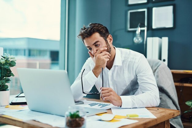 Ihm fällt es schwer, konzentriert zu bleiben Aufnahme eines jungen Geschäftsmanns, der gestresst aussieht, während er in einem Büro an einem Laptop arbeitet