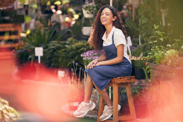 Ihr Lächeln erhellt den Raum Aufnahme einer schönen jungen Floristin, die in ihrem Garten sitzt