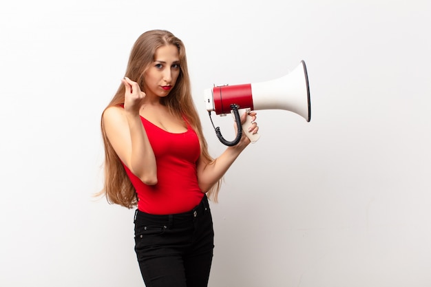 Ihre blonde Frau macht Capice oder Geldgeste und sagt Ihnen, Sie sollen Ihre Schulden bezahlen! ein Megaphon halten