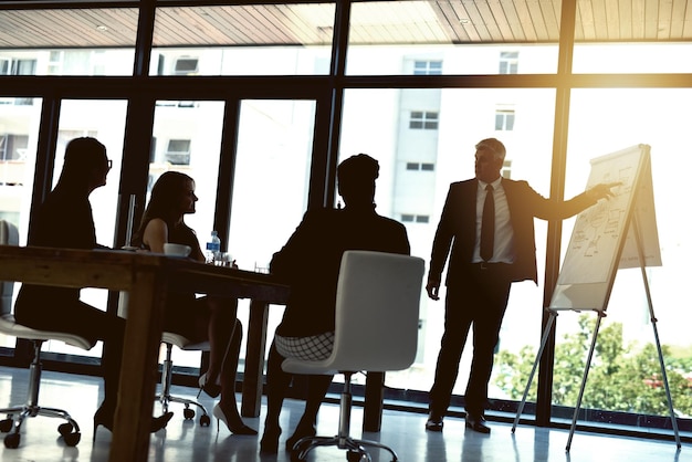 Ihre Pläne zusammenbringen Aufnahme eines Geschäftsmannes, der seinen Kollegen in einem Büro eine Präsentation gibt