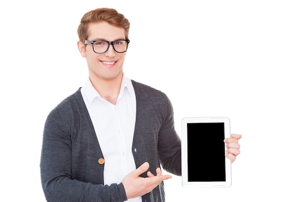 Ihre Werbung auf seinem Tablet. Fröhlicher junger Mann, der ein digitales Tablet hält und darauf zeigt, während er isoliert auf weiß steht