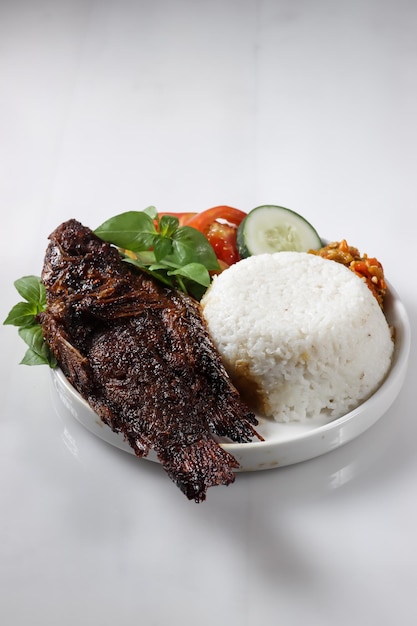 Ikan Nila Bakar dan nasi, pescado tradicional indonesio de tilapia nille a la parrilla con arroz.