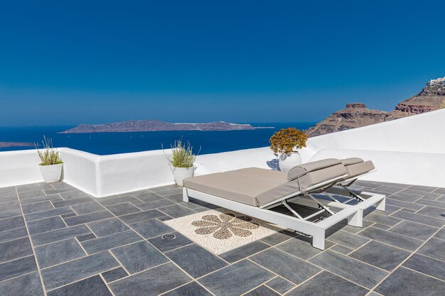 Ilha de Santorini, cena da caldeira de Oia, duas espreguiçadeiras, espreguiçadeiras, incrível horizonte ensolarado com vista para o mar relax