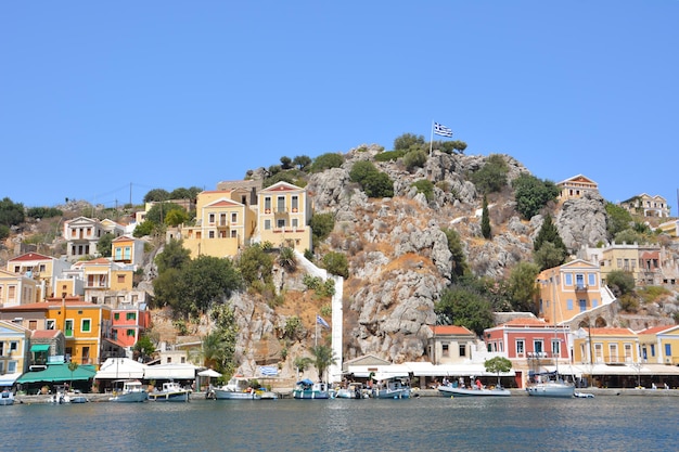 ilha grega Symi com casas multicoloridas, iates e escada com céu azul no fundo