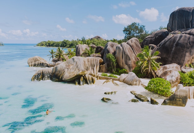 Ilha "La digue" nas Seychelles. Praia de prata com pedra granítica e selva. Homem curtindo férias na praia e se divertindo com caiaque. Vista aérea