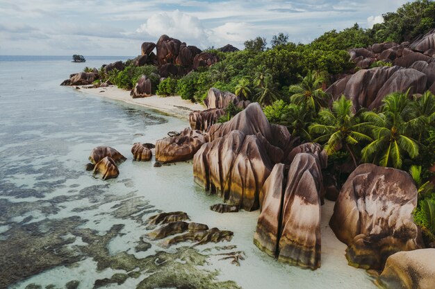 Ilha "La digue" nas Seychelles. Praia de prata com pedra granítica e selva. Vista aérea