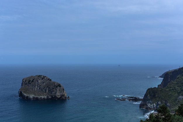 Foto ilha rochosa, linha do horizonte e costa rochosa