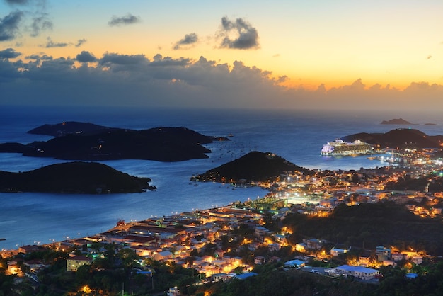 Ilhas Virgens St Thomas vista para a montanha do sol com nuvens coloridas, edifícios e litoral de praia.