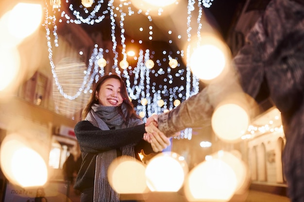 Iluminación artificial por guirnaldas Feliz pareja multirracial juntos al aire libre en la ciudad celebrando el Año Nuevo