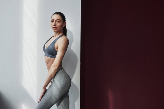 Iluminación natural. Bastante joven con buena forma de cuerpo fitness posando en la habitación