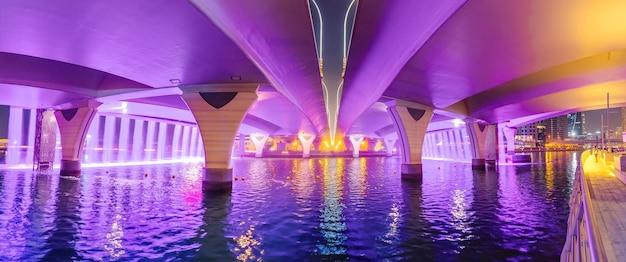 La iluminación de neón de una cascada artificial desde el puente sobre el Canal de Dubai es un lugar turístico popular que vale la pena visitar