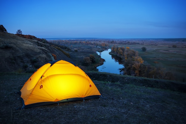 Iluminado dentro de la carpa naranja en una colina sobre el río