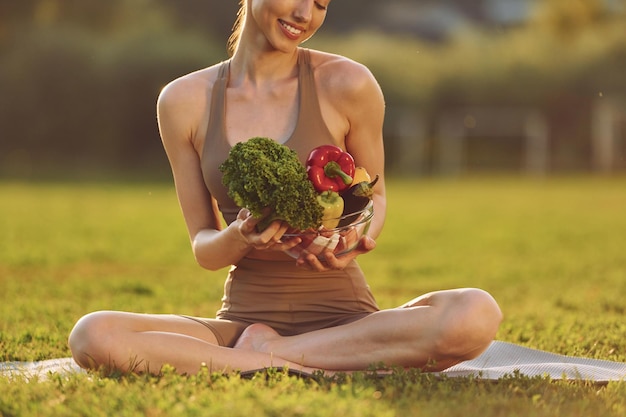 Iluminado por la luz del sol Mujer joven en ropa de yoga está al aire libre en el campo