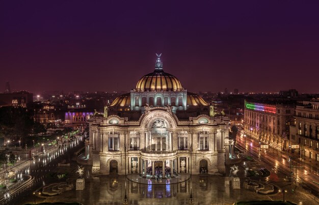 Foto iluminado palacio de bellas artes en medio de la ciudad por la noche