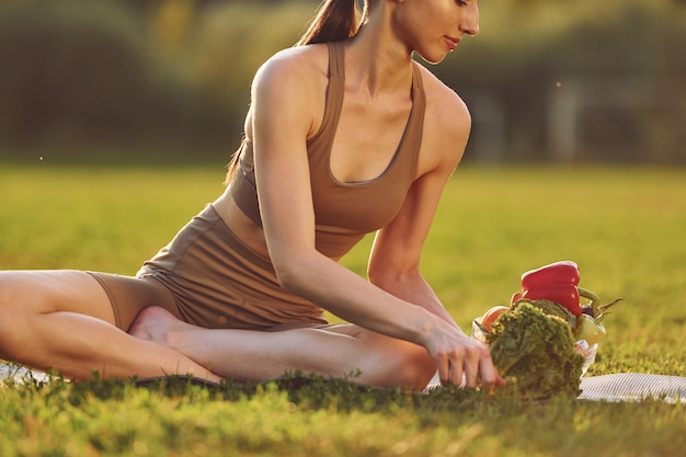 Iluminado pela luz do sol Jovem mulher com roupas de ioga está ao ar livre no campo