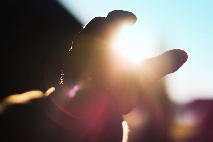 Foto ilusão óptica de mão recortada segurando o sol