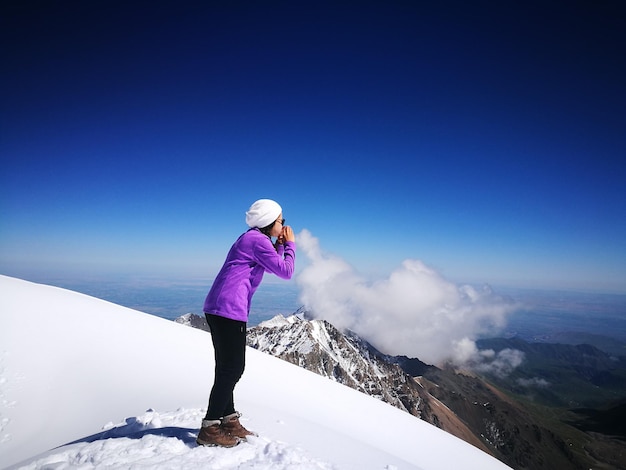 Ilusión óptica de una mujer soplando nubes contra el cielo