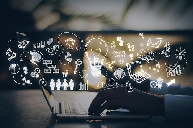 Ilustración de varios iconos de negocios y creatividad sobre una computadora portátil con la mano de una persona apuntando frente a un concepto de innovación de fondo borroso