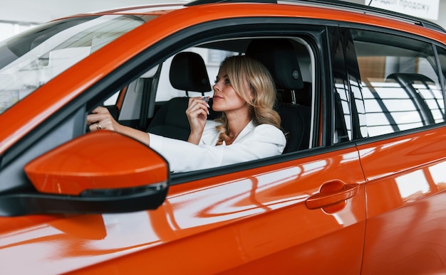 Im auto sitzen frau in formeller kleidung ist drinnen im autosalon