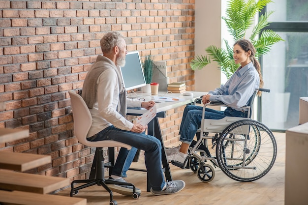 Im Büro. Behinderte junge Frau sitzt am Tisch im Büro