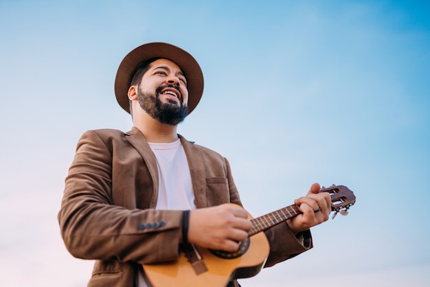 Im Freien eines jungen lateinamerikanischen Mannes, der Cavaquinho oder Ukulele spielt. Brasilianischer Musiker.