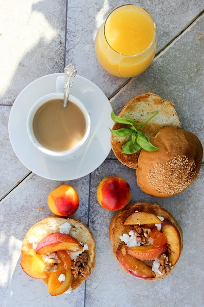 Im Freien Frühstück mit gegrillten Brötchen mit Ziegenfett, Obst, Nüssen, Orangensaft und Kaffee