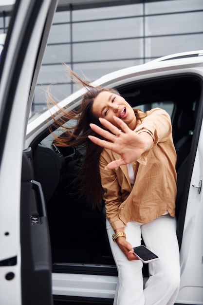 Im Freien gegen modernes Gebäude Modische schöne junge Frau und ihr modernes Automobil