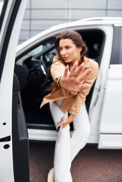 Im Freien gegen modernes Gebäude Modische schöne junge Frau und ihr modernes Automobil